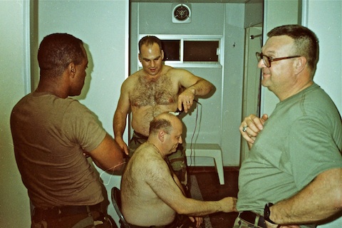 CPT Wojta shaving CPT Bartelme's bald spot, while CPT Yancy and SSG Gene Jakubenas look on.
