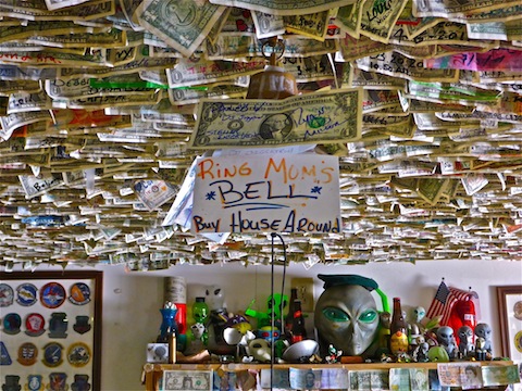 Alien knick-knacks, and maybe 20% of the bills stapled to the ceiling. Lots of military, fire & police patches as well.