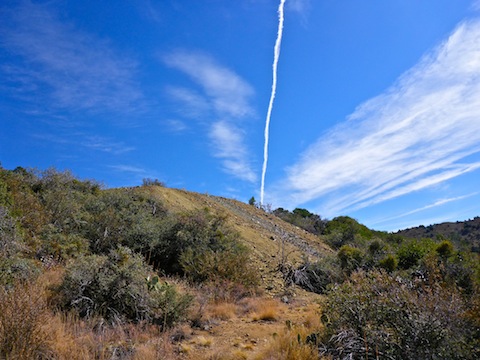 I love this shot of a contrail apparently shooting out of tailings pile.