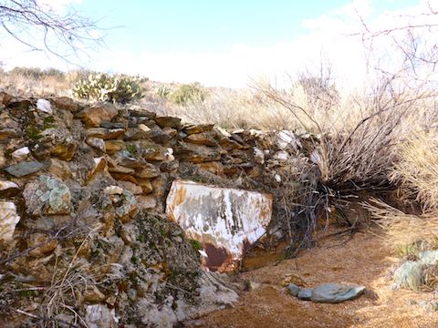 Sheet metal and man-made stone wall at old mining prospect.