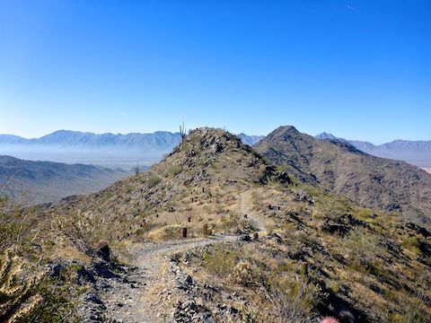 Heading west on Alta Trail, along the Ma Ha Tauk ridgeline. Maricopa Peak's summit is on the right. Pollution and the Sierra Estrella in the distance. 