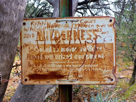Graffitied up sign marking the Hellsgate Wilderness boundary.