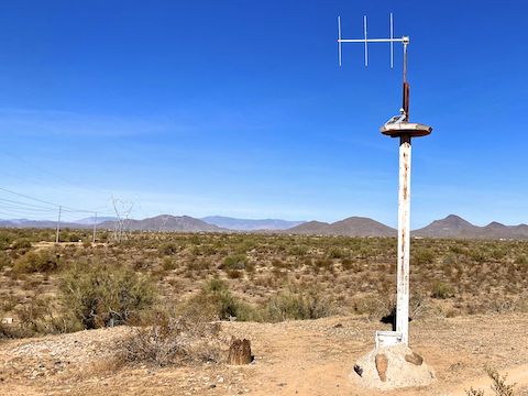 Maricopa County Flood Control District gauge 20507. If you go down & left, an official shortcut — ignore the “do not enter” signs — follows the powerline for ¼ mile across Cave Creek to Esplanade Trail, shaving two miles off this loop. Northeast (left to right) are Daisy Mountain, the Bradshaw Mountains, Apache Peak, and the various unnamed hills of Cave Creek Regional Park.