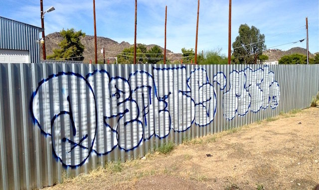 Throwup on wall of shady used car lot in Sunnyslope.